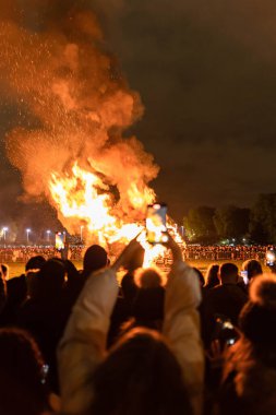 Young female recording a video with her phone of a bonfire during the new year's eve festivities