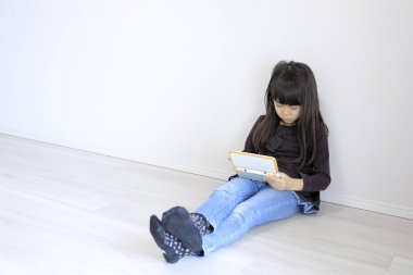 Yerde video oyun konsoluyla oynayan Japon kız (7 yaşında))