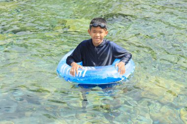 Japanese junior high school student playing in the river with floating tube (12 years old boy)