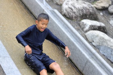 Japanese junior high school student playing in the river with water slide (12 years old boy)