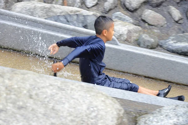 Japanese junior high school student playing in the river with water slide (12 years old boy)