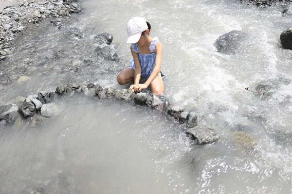 Japanese student girl damming river by stone (7 years old)