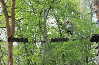 Japanese student girl playing at outdoor obstacle course on tree (7 years old)