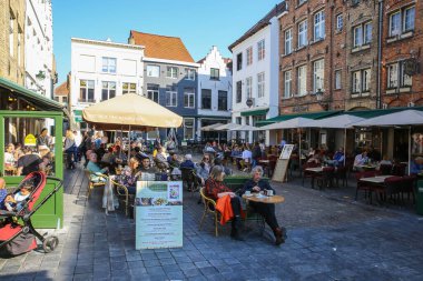 Brugge (Eiermarkt), Belçika - 9 Ekim. 2021: Restoranlar ve kafelerle pazar meydanına bakın, güneşli bir günde dışarıda oturan insanlar (merkezin solundaki kalabalığa odaklanın)