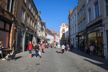 Brugge, Belçika - 9 Ekim. 2021: Eski şehir merkezindeki alışveriş caddesinde mavi berrak gökyüzü