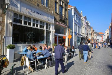 Brugge, Belçika - 9 Ekim. 2021: Eski şehir merkezindeki alışveriş caddesinde mavi berrak gökyüzü
