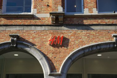 Brugge, Belçika - 9 Ekim. 2021: Eski tuğla bina cephesinde H ve M moda zinciri logosu