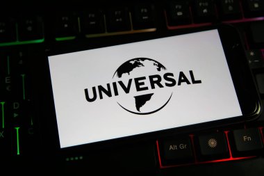 Viersen, Almanya - 9 Haziran. 2021: Cep telefonu ekranının kapatılması ve bilgisayar klavyesindeki film yapım şirketlerinin evrensel stüdyolarının logosu