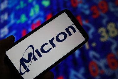 Viersen, Almanya - 6 Haziran. 2021: Cep telefonu ekranının kapatılması, mikron teknolojisi logosu, borsa grafiği arkaplanı