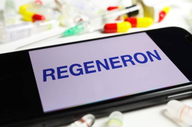 Viersen, Almanya - 1 Aralık. 2021: Rejeneron, serum şişeleri ve şırınga arkaplan logolu cep telefonu ekranının kapatılması