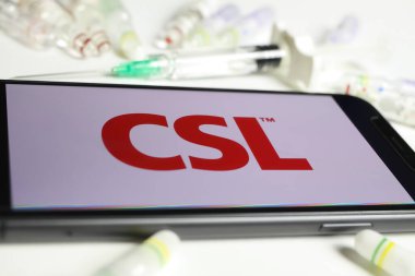 Viersen, Almanya - 1 Aralık. 2021: Cep telefonu ekranının CSL Behring logosu, serum şişeleri ve şırınga arkaplanı (S harfinin merkezine seçici odaklanma) ile kapatılması)