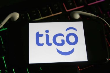 Viersen, Almanya - 9 Mayıs. 2021: Bilgisayar klavyesinde Tigo çevrimiçi müzik yayınlama servisinin logosu olan akıllı telefon ekranının kapatılması