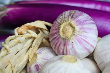 Beyaz pembe, sarımsaklı ampuller, bulanık mor patlıcan arkaplan.