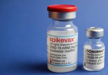 Viersen, Almanya - 9 Ocak. 2022: İki izole edilmiş mRNA aşı şişesinin (Moderna Spikevax ve Biontech Pfizer Comirnaty) kapatılması, mavi arkaplan