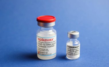 Viersen, Almanya - 9 Ocak. 2022: İki izole edilmiş mRNA aşı şişesinin (Moderna Spikevax ve Biontech Pfizer Comirnaty) kapatılması, mavi arkaplan