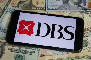 Viersen, Almanya - 9 Ocak. 2022: Cep telefonunun DBS bankası logosu ve Amerikan kağıt banknotları ile kapatılması