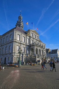 Maastricht, Hollanda - 13 Şubat. 2022: 17. yüzyıldan itibaren belediye binasındaki pazar meydanının mavi kış gökyüzüne karşı görüntüsü