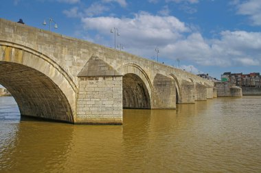 Maastricht (Sint Servaasbrug), Hollanda - 13 Şubat. 2022: Mavi kış gökyüzüne karşı eski kemerli kireçtaşlı yaya köprüsündeki Maas Nehri 'ne bakın