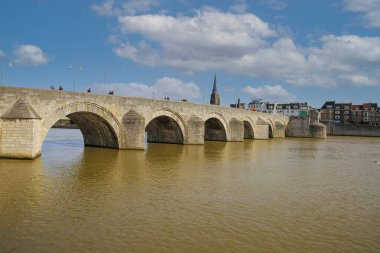 Maastricht (Sint Servaasbrug), Hollanda - 13 Şubat. 2022: Mavi kış gökyüzüne karşı eski kemerli kireçtaşlı yaya köprüsündeki Maas Nehri 'ne bakın