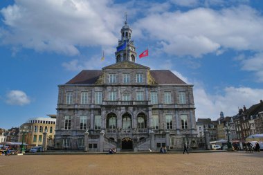 Maastricht, Hollanda - 13 Şubat. 2022: 17. yüzyıldan itibaren belediye binasının pazar meydanının üzerinde mavi kış sabahı gökyüzüne (büyük binanın ön cephesine odaklan)