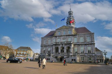Maastricht, Hollanda - 13 Şubat. 2022: 17. yüzyıldan itibaren belediye binasının pazar meydanının üzerinde mavi kış sabahı gökyüzüne (büyük binanın ön cephesine odaklan)