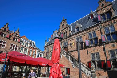 Nijmegen (Grote Markt), Hollanda - 27 Şubat. 2022: Mavi gökyüzüne karşı ortaçağ kırmızı tuğla cephelerine bakın