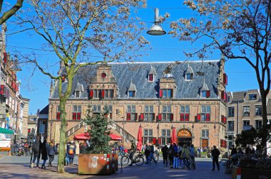 Nijmegen (grote markt), Hollanda - 27 Şubat. 2022: Güneşli bir günde kafeler, restoranlar ve eski ortaçağ binalarıyla dolu işlek pazar meydanını görmek