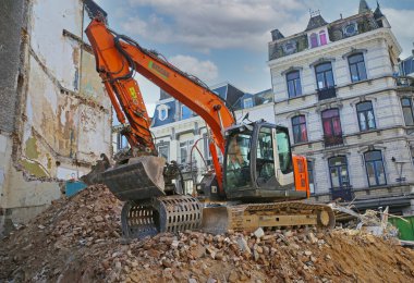 Liege, Belçika - 5 Mart. 2022: Yıkım çalışmaları sırasında şehir merkezinde moloz yığınları inşa eden kazıcıya bakın