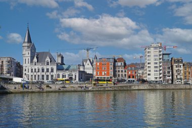 Liege, Belçika - 5 Mart. 2022: Şehir merkezinin rıhtımındaki nehir meuse üzerinde mavi gökyüzüne karşı tarihi bina ile görsellik