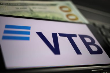 Viersen, Almanya - 9 Mart. 2022: Rus VTB bankasının logosuna sahip bilgisayar klavyesindeki cep telefonunun kapatılması, bulanık dolar banknotu geçmişi