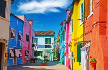 Venedik (Burano), İtalya - 9 Mayıs. 2019: Açık mavi gökyüzüne karşı parlak renkli renkli evlerle boş sokağa bak