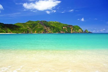 Güzel tropikal göl, beyaz kumsal, turkuaz su, yeşil kaya tepesi, mavi yaz gökyüzü - Kuta, Endonezya