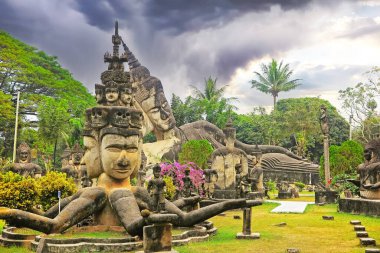 Hindu ve Budist mitolojik yaratıkların bulunduğu mistik tropik bahçe taş heykeller, fırtına bulutları - Buda Parkı (Wat Xieng Khuan), Vientiane, Laos