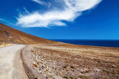 Güzel sahil kıyısı toprak yolu, kurak arazi, mavi Atlantik okyanusu - Punta de Jandia 'ya yolculuk, Fuerteventura