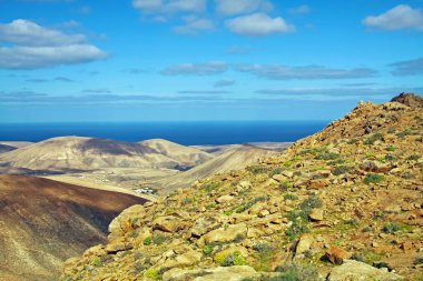 Güzel dramatik gerçeküstü kıyı manzarası, kuru engebeli dağlar, bulanık okyanus, mavi gökyüzü bulutları - Betancuria (Montana atalaya), Fuerteventura