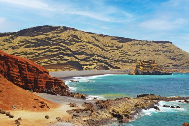 Etkileyici engebeli sarp kayalıklarla çevrili güzel tenha bir göl, farklı renkler, kırmızı kaya, boş siyah kumsal - El Golfo, Lanzarote