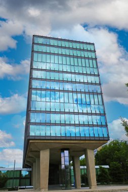 TU Eindhoven (teknik üniversite), Hollanda - 19 Temmuz. 2022: Hollanda kampüsünde gökyüzü bulutları yansıtan modern mimari cam cephe binası