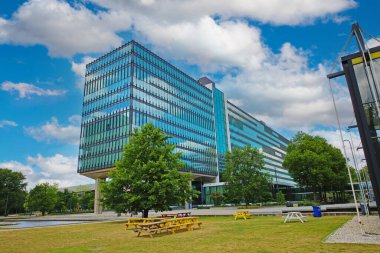 TU Eindhoven (technical university), Netherlands - July 19. 2022: Modern architecture glass facade building with sky clouds reflection on dutch campus