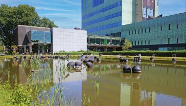 TU Eindhoven (technical university), Netherlands - July 17. 2022: Modern architecture auditorium building with idyllic water pond on dutch campus