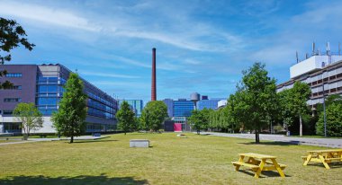 TU Eindhoven (teknik üniversite), Hollanda - 17 Temmuz. 2022: Modern mimarlık binaları, Hollanda kampüs parkındaki eski tuğla bacalar