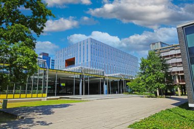 TU Eindhoven (teknik üniversite), Hollanda - 17 Temmuz. 2022: Hollanda kampüsünde mavi gökyüzü bulutları olan modern mimari cam ön cephe oditoryum binası