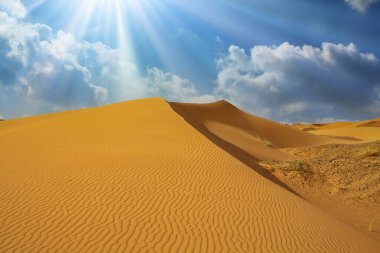 Beautiful african desert landscape, triangle shape yellow sand dune, dramatic sky clouds, sun rays backlight - Morocco, Erg Chebbi, North Africa