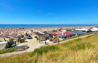 Zandvoort, Netherlands - August 12. 2022: View from dunes on crowded dutch north sea city beach on sunny summer weekend