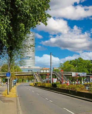 Cologne (Deutzer Freiheit), Germany - July 9. 2022: Street in city center, subway station, train, triangle tower, pedestrian crossing bridge, blue summer sky