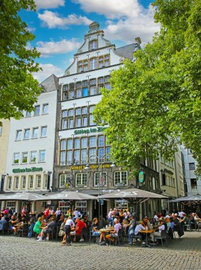 Cologne (Heumarkt), July 9. 2022: View over square on medieval brew house gilden im Zims, people sitting outside