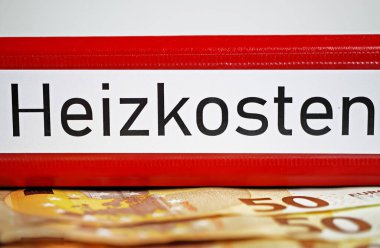 Almanca Heizkosten (engl.) sözcüğüyle izole edilmiş kırmızı dosya klasörünün kapatılması. Çeviri: Isıtma maliyetleri), euro nakit para banknotları