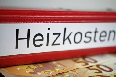 Almanca Heizkosten (engl.) sözcüğüyle izole edilmiş kırmızı dosya klasörünün kapatılması. Çeviri: Isıtma maliyetleri), euro nakit para banknotları