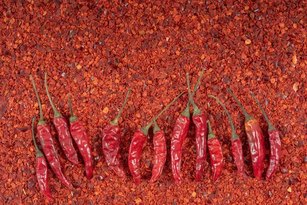 Background and texture of red hot chilli powder on which some hot dry chillies lie
