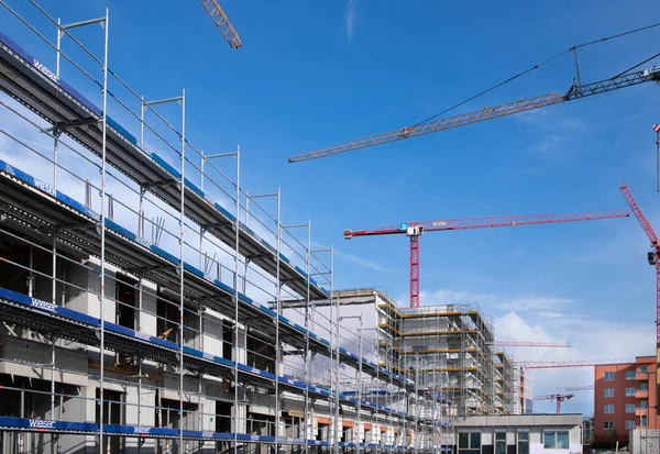 慕尼黑正在建造许多新房屋 一个有新建筑和脚手架的大建筑工地 有一条路和许多起重机在蓝天的映衬下 — 图库照片