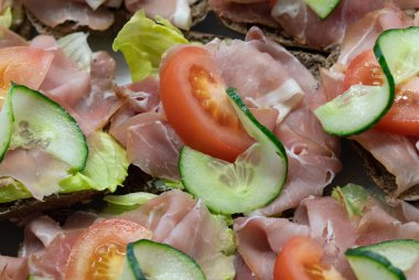 Jambon, salatalık ve domatesli birkaç rulo yan yana..